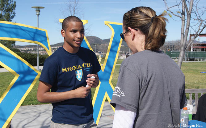 A member of the fraternity Sigma Chi at a recruiting booth on campus.