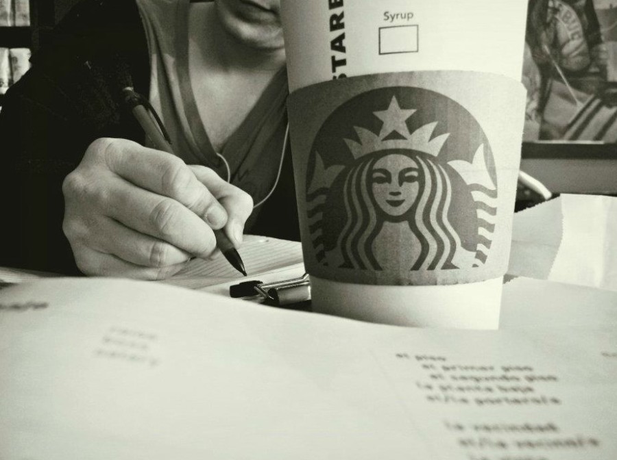 Close-up of Starbucks coffee cup with a student doing homework in the background