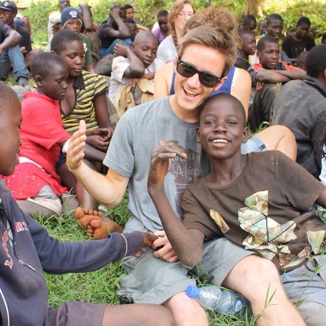College student from CSUSM sitting among children from Ugandan village