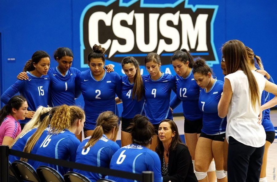 Women’s volleyball huddle around the head coach.