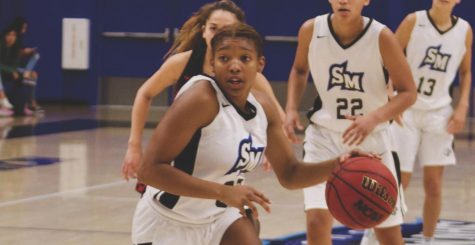 Athletics Dynnah Buckner (#32) dribbles across the court.