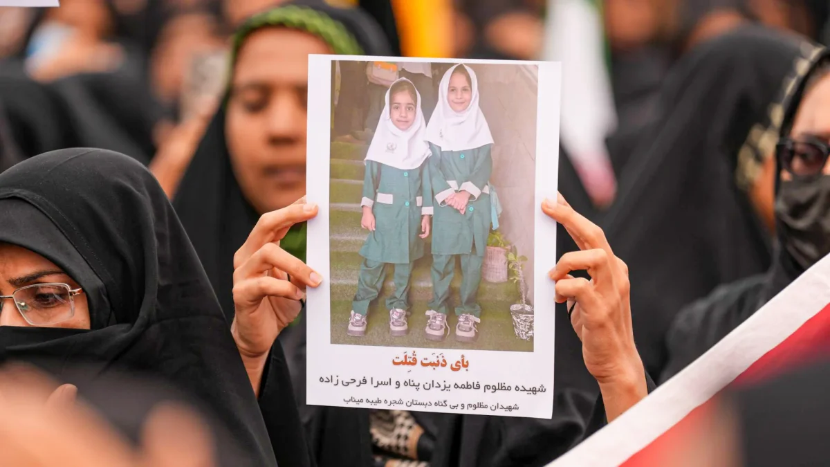 Mourners in Minab, Iran holding a portrait of students killed in a U.S.-Israeli airstrike on a girls' school.